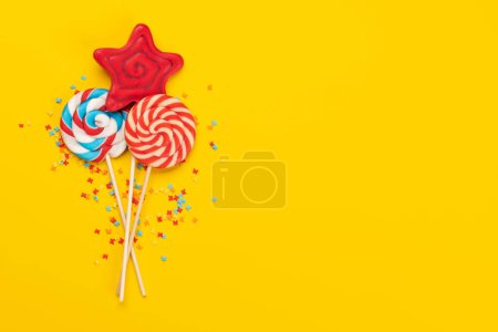 Téléchargez les photos : Various candy sweets and lollipops on yellow background and copy space for your text. Flat lay - en image libre de droit