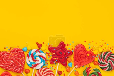 Photo for Various candy sweets and lollipops on yellow background and copy space for your text. Flat lay - Royalty Free Image