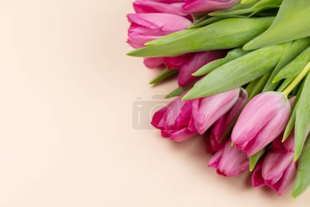 Foto de Pink tulip flowers bouquet on beige background. Flat lay with copy space - Imagen libre de derechos