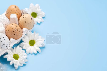 Téléchargez les photos : Easter eggs and flowers on a blue background with space for your greetings - en image libre de droit