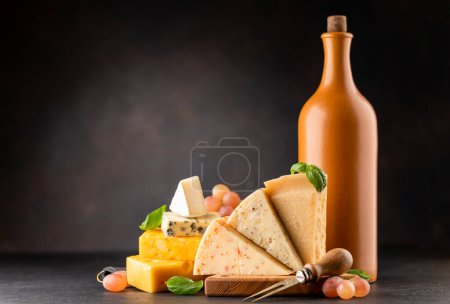 Photo for Various cheese on board and wine. Over dark background with copy space - Royalty Free Image