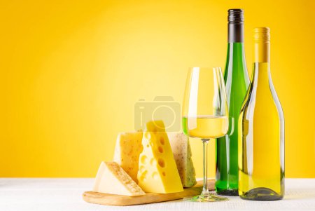 Photo for Various cheese on board and white wine. Over yellow background with copy space - Royalty Free Image
