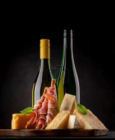 Photo for Antipasto board with various cheese and wine bottles - Royalty Free Image