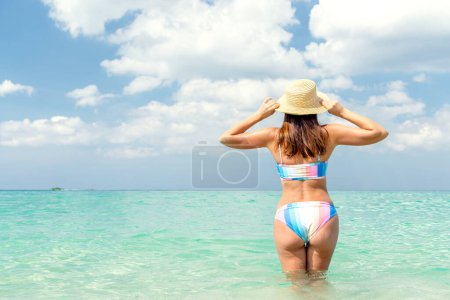 Photo for Back of beautiful girl in bikini standing in the sea. Enjoy and relax in summer with copy space - Royalty Free Image