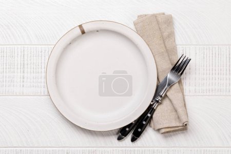 Téléchargez les photos : Empty plate with fork and knife on white wooden table. Flat lay with copy space - en image libre de droit