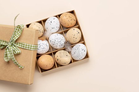 Foto de Caja de regalo con huevos de Pascua sobre fondo beige con espacio para tus saludos. Puesta plana - Imagen libre de derechos