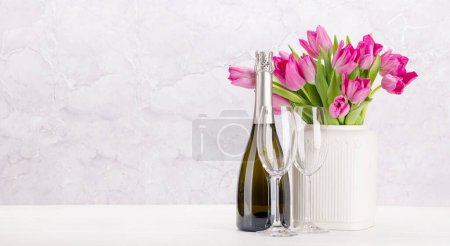 Foto de Ramo de flores de tulipán rosa fresco y champán. En mesa de madera blanca con espacio para copiar - Imagen libre de derechos