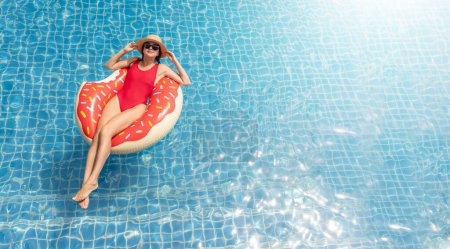 Foto de Beautiful young woman with inflatable donut ring relaxing in swimming pool. Summer vacation. Top view with copy space - Imagen libre de derechos