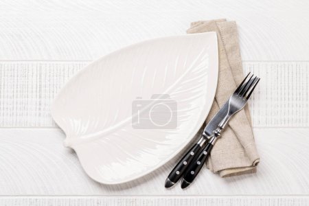 Téléchargez les photos : Empty leaf shaped plate with fork and knife on white wooden table. Flat lay with copy space - en image libre de droit