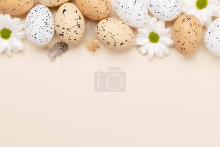 Téléchargez les photos : Easter eggs and flowers on a beige background with space for your greetings. Flat lay - en image libre de droit