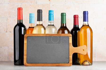 Foto de Various wine bottles on stone table. With chalkboard for your text - Imagen libre de derechos