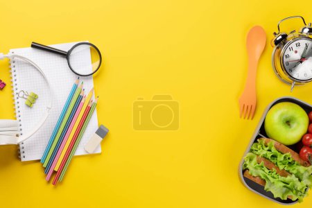 Téléchargez les photos : Fournitures scolaires, papeterie et boîte à lunch sur fond jaune. Éducation et nutrition. Pose plate avec espace vide - en image libre de droit