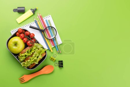 Photo for School supplies, stationery, and lunch box on green background. Education and nutrition. Flat lay with blank space - Royalty Free Image