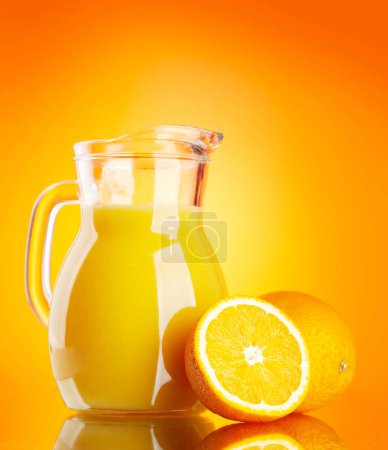Téléchargez les photos : Jus d'orange frais dans un pichet en verre sur fond d'orange - en image libre de droit