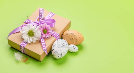 Foto de Caja de regalo, huevos de Pascua y flores sobre un fondo verde con espacio para tus saludos - Imagen libre de derechos