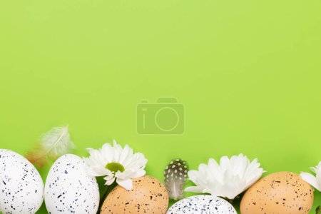 Foto de Huevos de Pascua y flores sobre un fondo verde con espacio para sus saludos. Puesta plana - Imagen libre de derechos