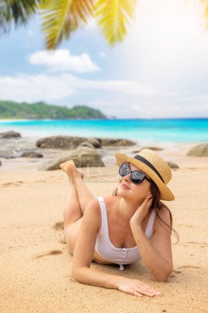 Téléchargez les photos : Woman lying on the sea beach enjoying and relaxing in summer - en image libre de droit