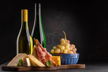 Foto de Antipasto board with various cheese and wine bottles - Imagen libre de derechos