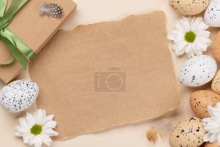Téléchargez les photos : Gift box, Easter eggs and flowers on a beige background with space for your greetings. Flat lay - en image libre de droit