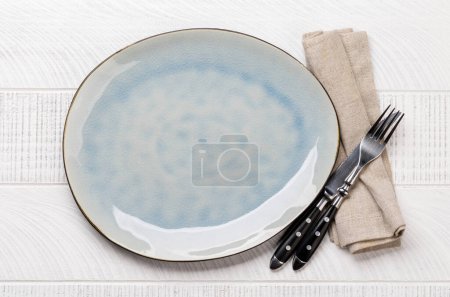 Téléchargez les photos : Empty plate with fork and knife on white wooden table. Flat lay with copy space - en image libre de droit