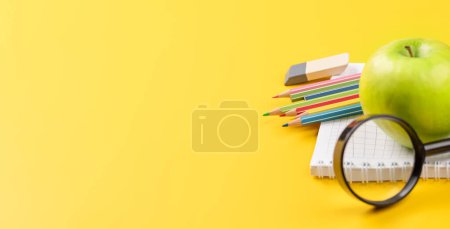 Foto de Material escolar, papelería y manzana sobre fondo amarillo. Educación y nutrición. Con espacio en blanco - Imagen libre de derechos