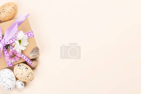 Photo for Gift box, Easter eggs and flowers on a beige background with space for your greetings. Flat lay - Royalty Free Image