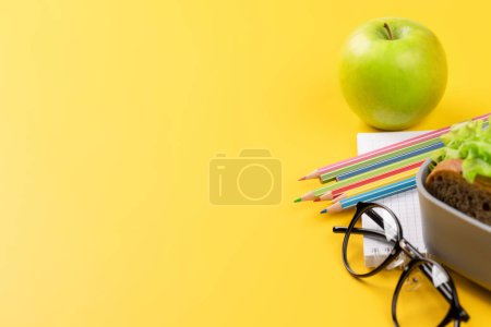 Foto de School supplies, stationery, and lunch box on yellow background. Education and nutrition. With blank space for your text - Imagen libre de derechos