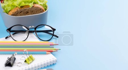 Photo for School supplies, stationery, and lunch box on blue background. Education and nutrition. With blank space for your text - Royalty Free Image