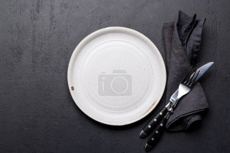 Téléchargez les photos : Assiette vide avec fourchette et couteau sur table en pierre sombre. Pose plate avec espace de copie - en image libre de droit