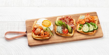 Photo for Breakfast waffles with fried eggs, salmon, bacon, cucumber and prawns. Top view - Royalty Free Image