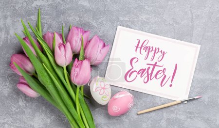 Téléchargez les photos : Œufs de Pâques colorés, tulipes et carte de vœux sur table en pierre. Vue du dessus plat lay - en image libre de droit