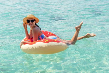 Photo for Beautiful young woman with inflatable donut ring relaxing in sea. Summer vacation - Royalty Free Image