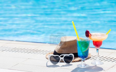 Foto de Dos copas de cóctel de colores en el borde de la piscina. Con espacio de copia - Imagen libre de derechos