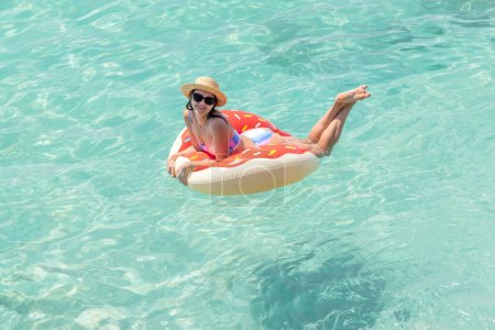 Photo for Beautiful young woman with inflatable donut ring relaxing in sea. Summer vacation - Royalty Free Image