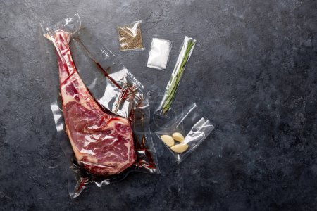Photo for Raw Tomahawk beef steak vacuum packed and spices. Ready for grilling. Flat lay - Royalty Free Image