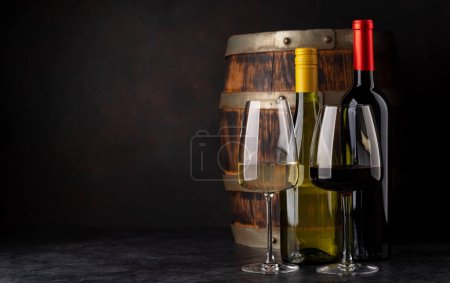 Foto de Botellas de vino blanco y tinto frente al barril de vino. Con espacio de copia - Imagen libre de derechos