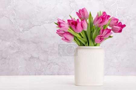 Foto de Fresh pink tulip flowers bouquet. On white wooden table with copy space - Imagen libre de derechos