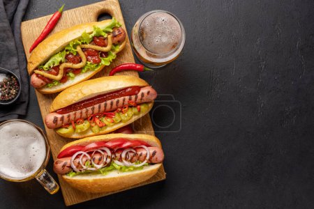 Téléchargez les photos : Divers hot dog et bière. Hotdogs faits maison sur planche à découper. Pose plate avec espace de copie - en image libre de droit