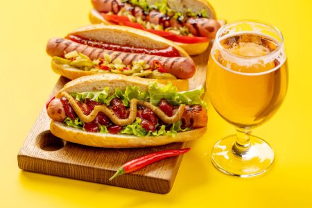 Téléchargez les photos : Divers hot dog et bière. Hotdogs faits maison sur planche à découper - en image libre de droit