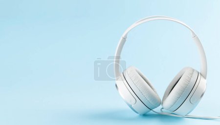 Foto de Auriculares blancos sobre fondo azul con espacio para copiar. Podcast, audiolibro o plantilla de música - Imagen libre de derechos