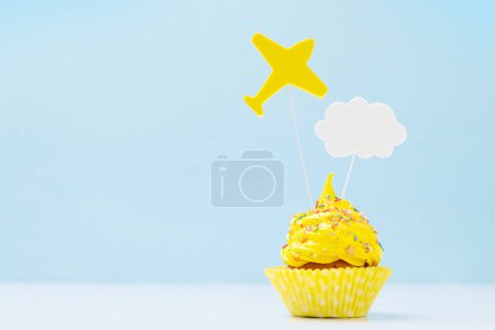 Foto de Cupcake crema amarilla con decoración sobre fondo azul con espacio para copiar - Imagen libre de derechos