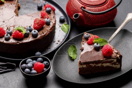 Téléchargez les photos : Dessert au gâteau au chocolat avec baies fraîches et théière - en image libre de droit