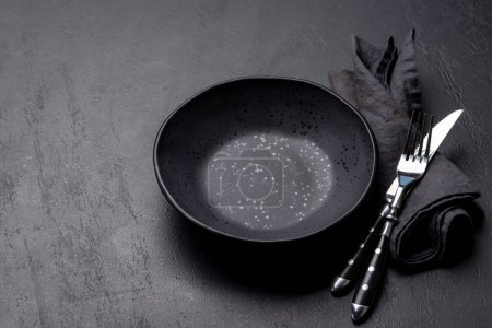 Photo for Empty plate with fork and knife on dark stone table. With copy space - Royalty Free Image
