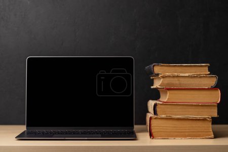 Photo for Laptop with black screen and stack of old books. With space for your text or app. Learn and work concept - Royalty Free Image
