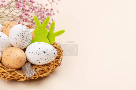 Foto de Huevos de Pascua y flores sobre fondo beige con espacio para tus saludos - Imagen libre de derechos