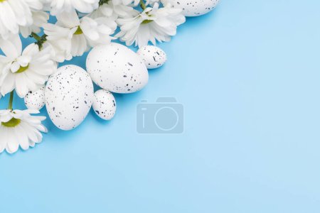 Foto de Huevos de Pascua y ramo de flores sobre un fondo azul con espacio para sus saludos. Puesta plana - Imagen libre de derechos
