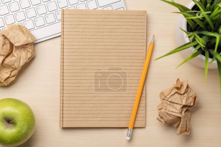 Foto de Vista superior de bloc de notas en blanco, teclado, anteojos y papeles arrugados en el escritorio, que representa intentos infructuosos de escritura - Imagen libre de derechos