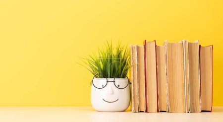 Photo for Old books on a table, potted plant with face and glasses and copy space for your text - Royalty Free Image