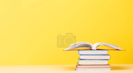 Foto de Montón de libros en el escritorio y espacio para la creatividad. Sobre fondo amarillo - Imagen libre de derechos