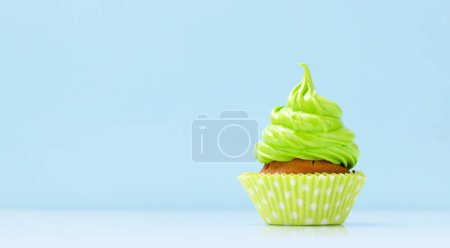 Foto de Crema verde cupcake sobre fondo azul con espacio para copiar - Imagen libre de derechos